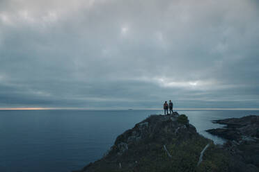 Male friends standing on rock formation during adventurous trip at dusk - MASF27453