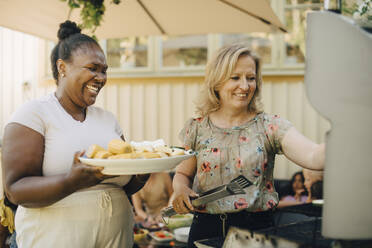 Happy women preparing food on barbecue grill during dinner party - MASF27477