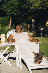 Mittlere erwachsene Frau lachend auf einem Liegestuhl sitzend während einer Gartenparty - MASF27484