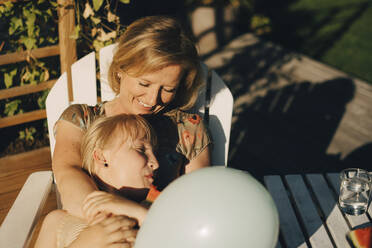Lächelnde Mutter mit Tochter auf der Terrasse im Hinterhof - MASF27491