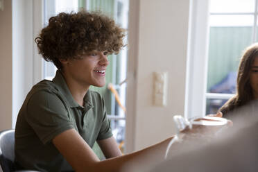 Smiling teenage boy sitting by sister at home - MASF27504