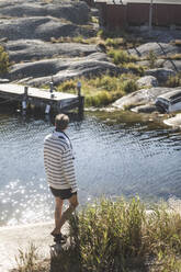 Mid adult man walking by river on sunny day - MASF27577