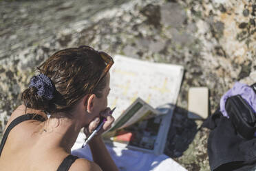 Woman with hand on chin reading newspaper at island - MASF27585