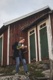 Frau mit Frühlingszwiebel, die an einer Hütte vorbeiläuft - MASF27598