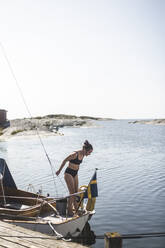 Mittlere erwachsene Frau im Bikini auf einem Segelboot an einem sonnigen Tag - MASF27617