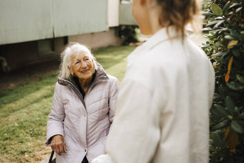 Lächelnde ältere Frau im Gespräch mit einer Betreuerin im Vorgarten - MASF27691