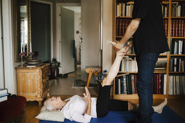 Midsection of male caregiver guiding senior woman while exercising at home - MASF27728