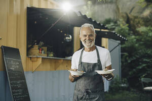 Portrait of senior male owner with food by truck - MASF27795