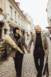 Senior couple holding hands while exploring city during vacation - MASF27832