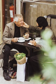 Elderly couple talking while having breakfast at sidewalk cafe - MASF27838