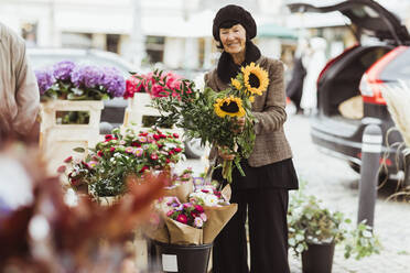 Lächelnde ältere Frau kauft Blumen auf dem Markt - MASF27842