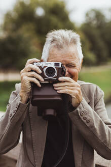 Älterer Mann beim Fotografieren mit Kamera am Wochenende - MASF27852