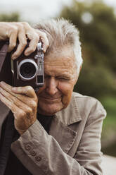 Älterer Mann, der im Urlaub durch die Kamera fotografiert - MASF27853
