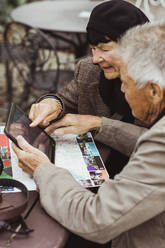 Elderly man and woman using GPS navigation through digital tablet at table - MASF27860