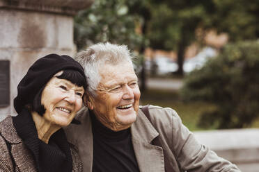 Cheerful senior couple looking away while sitting in park - MASF27864