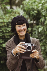 Lächelnde ältere Frau mit Kamera im Park - MASF27867