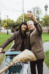 Älteres Paar, das am Wochenende im Park ein Selfie mit einem Elektrofahrrad per Smartphone macht - MASF27888