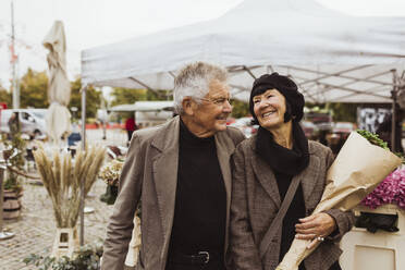 Fröhliches älteres Paar, das im Urlaub auf dem Markt spazieren geht - MASF27894