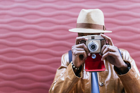 Faceless male photographer taking picture on photo camera near colorful wall on street - ADSF32582