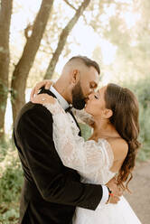 Bride and groom kissing in park - ISF25481