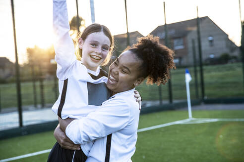 UK, Happy female soccer players (10-11, 12-13) embracing in field - ISF25499