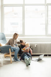 Parents reading book with daughter at home - GUSF06656