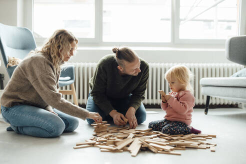 Cute girl playing jenga with parents at home - GUSF06658