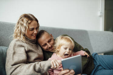 Happy family using tablet PC on sofa at home - GUSF06660