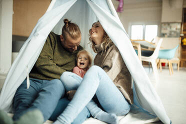 Verspielte Familie, die sich im Zelt zu Hause vergnügt - GUSF06672