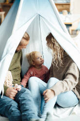 Girl looking at parents sitting inside tent - GUSF06679