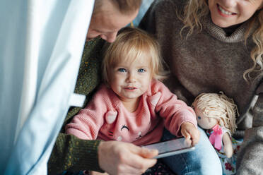 Nettes Mädchen hält digitales Tablet mit Eltern zu Hause - GUSF06681