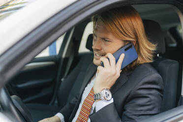 Geschäftsmann, der im Auto mit seinem Handy telefoniert - JRVF02217