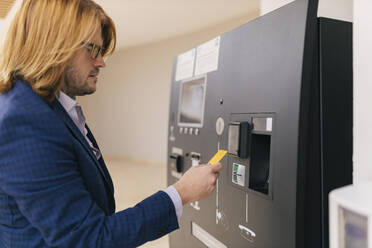 Businessman using credit card at ATM machine - JRVF02228