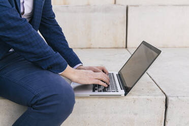 Businessman using laptop on steps - JRVF02242