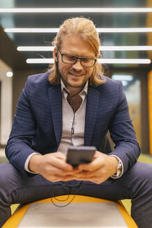 Lächelnder Geschäftsmann mit Mobiltelefon in der U-Bahn-Station - JRVF02258