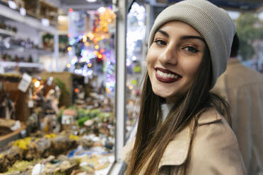 Junge Frau lächelt in einem Geschäft zur Weihnachtszeit - JRVF02271