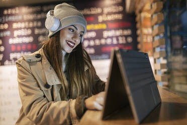 Frau mit Kopfhörern und Touchscreen-Laptop in einem Café - JRVF02294