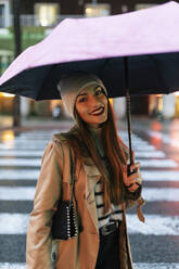 Frau mit Regenschirm auf der Straße in der Stadt stehend - JRVF02298