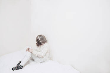Traurige Frau in Plastik eingewickelt sitzt an der Wand auf einer Bettdecke - SVCF00078