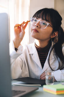 Junge Wissenschaftlerin mit Brille, die im Labor nachdenkt - ASGF01875