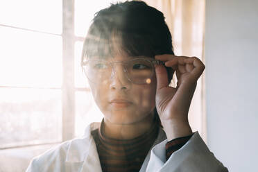 Junge Wissenschaftlerin mit Brille, die im Labor wegschaut - ASGF01886