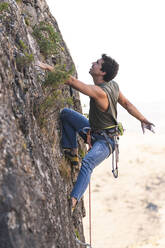 Mann mit Sicherheitsgurt beim Klettern auf einem Felsberg - JAQF01010