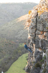 Hiker with climbing rope hanging on rock mountain - JAQF01014