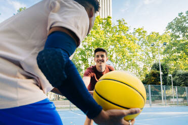 Multiracial Freunde Spieler laufen zusammen mit Ball beim Basketball spielen auf Sportplatz in sonnigen Tag - ADSF32695