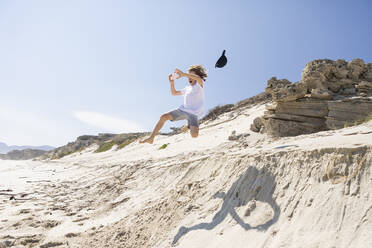 Ein Junge springt von einer Sanddüne in den weichen Sand darunter. - MINF16477