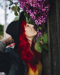 Frau mit rotem Haar riecht an Blumen - MRRF01753