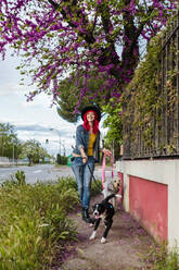 Woman running with dogs on footpath near fence - MRRF01755