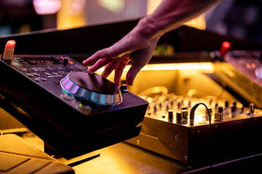 Crop unerkennbar männlichen DJ Auflegen und Mischen von Musik am Plattenteller während der Party in beleuchteten Nachtclub - ADSF32761