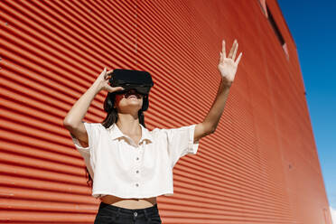 Woman using virtual reality headset in front of wall - EGAF02469