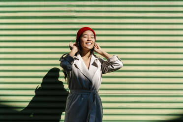 Lächelnde Frau vor einer grünen Wand stehend - EGAF02485